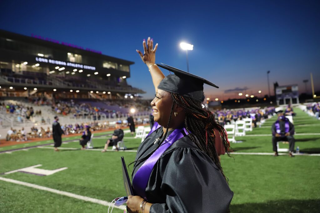 female waving graduation 1024x683 1