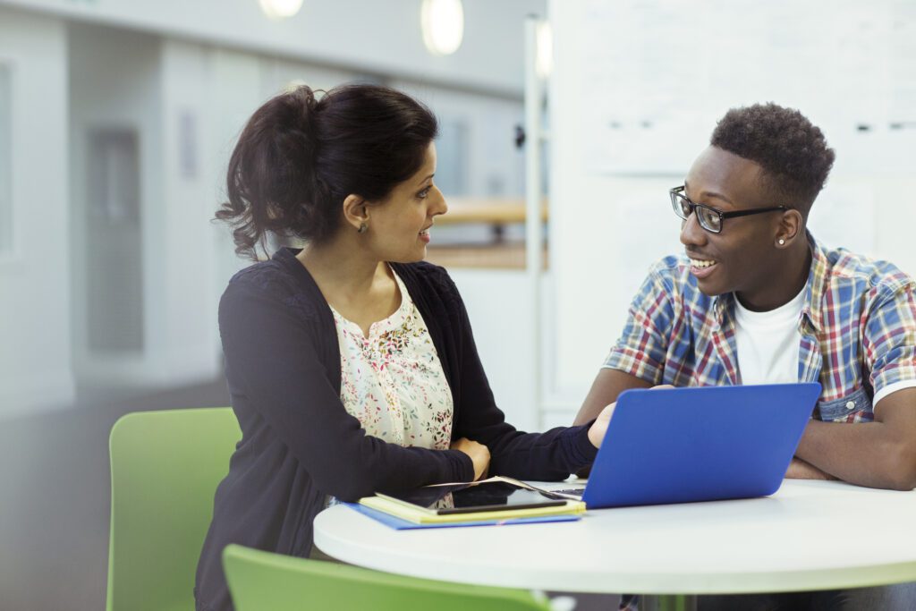 Teacher and student sitting together with laptop and tablet