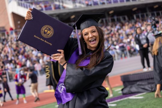 Joyous student displaying her diploma cover at Commencement