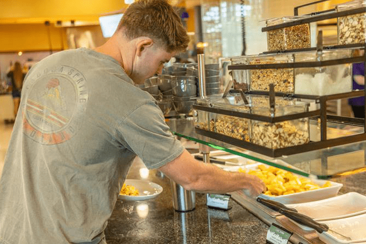 male student getting food in dining hall min