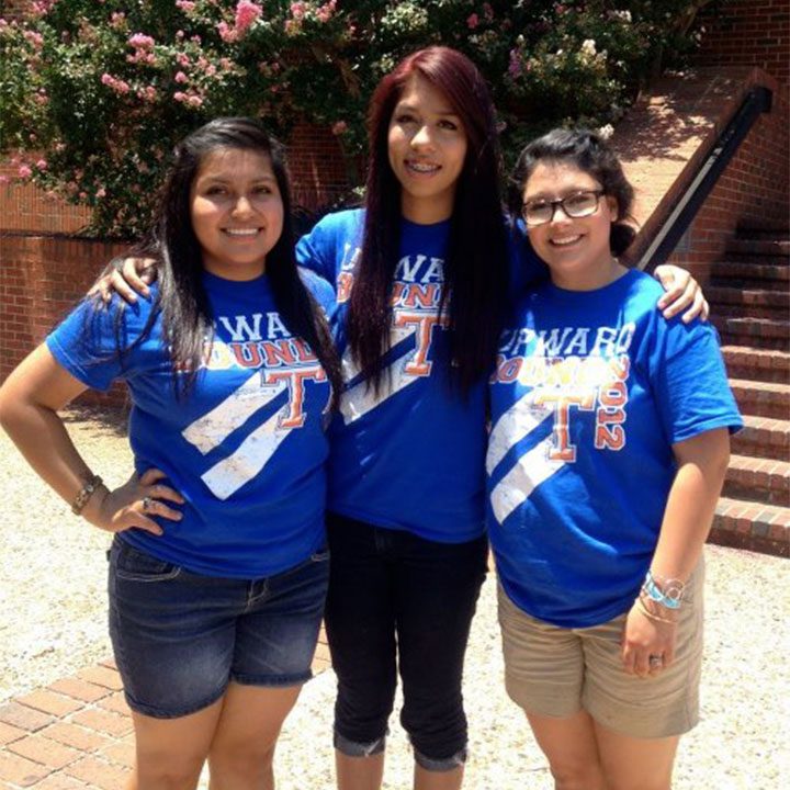 Three Upward Bound (UB) Girls stand side by side smiling while wearing matching UB Program Shirts