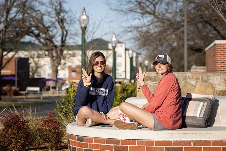 students sitting together on campus posing with states up